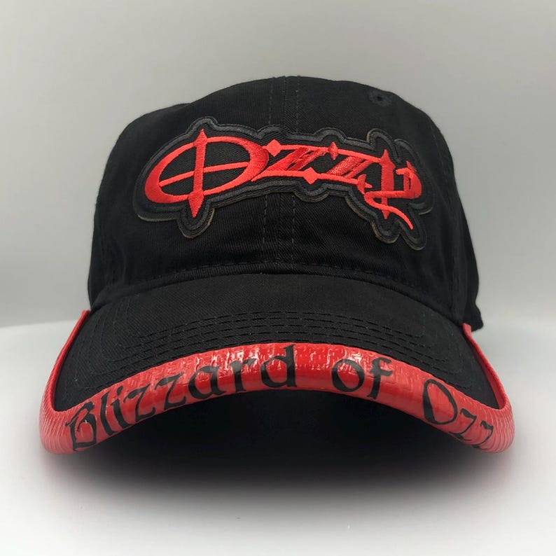 May include: Black baseball cap with red embroidered "Ozzy" logo on the front. The brim is red with the words "Blizzard of Ozz" in red lettering. A classic, stylish accessory.