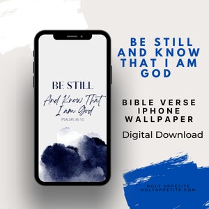 May include: A black iPhone displays a digital wallpaper with the text "Be Still And Know That I Am God" in a script font. The background features dark blue watercolor-style blotches. Additional text reads "Bible Verse iPhone Wallpaper" and "Digital Download."