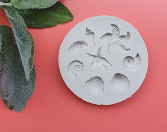 May include: White silicone mold with nine different sea-themed shapes, including seashells, starfish, and a nautilus shell.