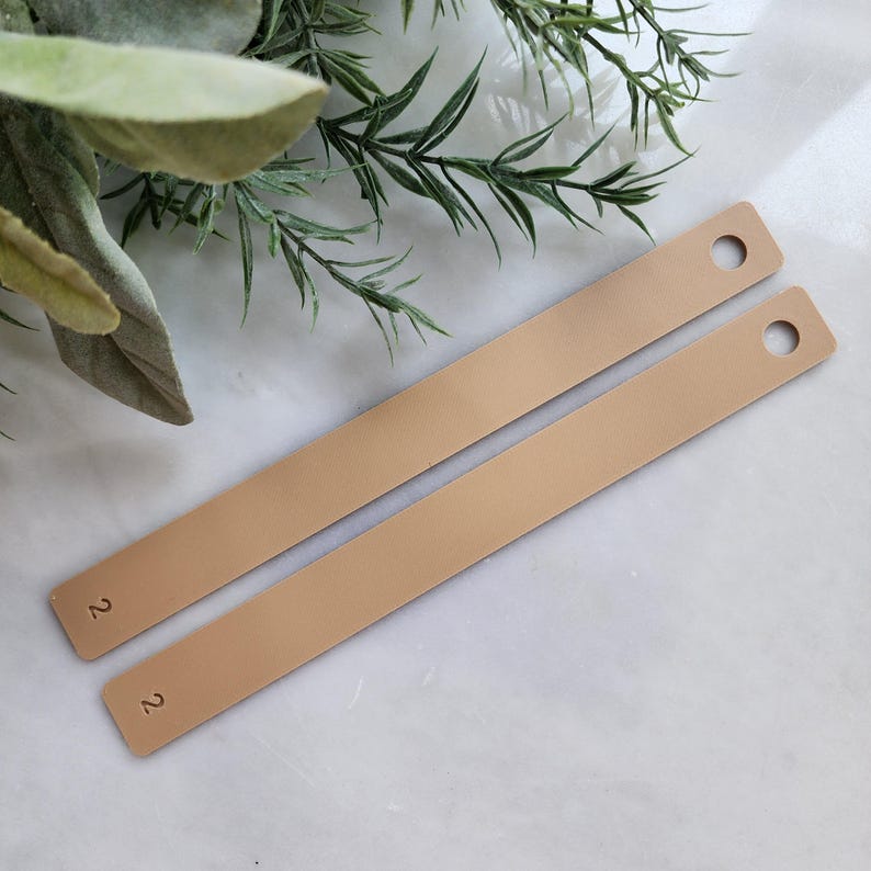 May include: Two beige metal strips with rounded ends and a hole punched near each end. The strips are labeled with the number "2" on each side.