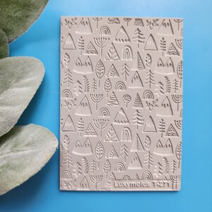 May include: A grey silicone mould with a repeating pattern of mountains, trees, and rainbows. The mould is labelled "Luxymolds T-271".