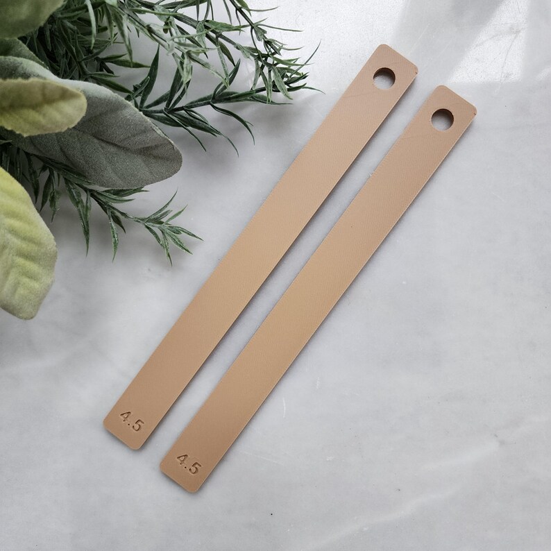 May include: Two beige leather straps with holes and the number 4.5 printed on each strap.