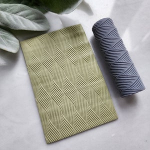 May include: A green textured rolling pin and a matching textured sheet of polymer clay. The rolling pin is used to create a textured pattern on the clay.