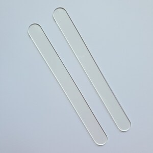 Puede incluir: Dos varillas para remover de acr&iacute;lico transparente, de forma rectangular y con extremos redondeados. Las varillas son transparentes y parecen estar hechas de un material liso y pulido. Est&aacute;n colocadas en diagonal sobre un fondo blanco.