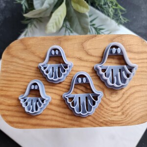 Könnte beinhalten: Vier violette Plastik-Keksstempel auf einer Holzoberfläche. Die Stempel haben einen gewellten Rand und zwei kleine Kreise für Augen.