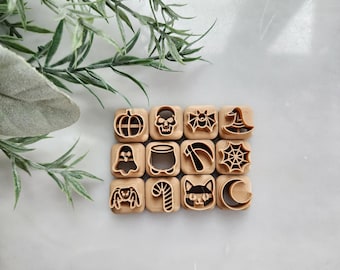 May include: A set of 12 wooden Halloween cookie cutters with various designs, including a pumpkin, skull, bat, witch hat, spider web, ghost, cauldron, candy cane, cat, and crescent moon.