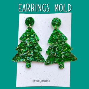 May include: A pair of green glitter Christmas tree earrings with gold jump rings. The earrings are on a white card with the text "EARRINGS MOLD" and "@luxymolds".