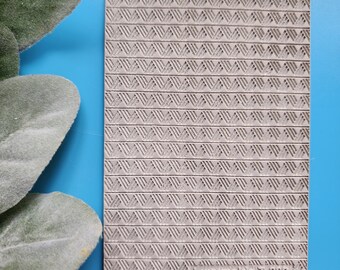 May include: A gray silicone mold with a repeating pattern of small triangles. The mold is rectangular and has the text "Luxy molds T-289" in the bottom right corner.