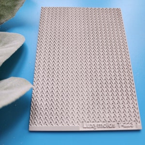 May include: A white silicone mold with a herringbone pattern. The mold is labeled "Luxy Molds T-223".