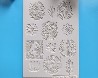 Pode incluir: Um molde de silicone branco com 12 desenhos diferentes, incluindo flores, pássaros e uma mulher. O molde é etiquetado como "Luxy Molds T-578".