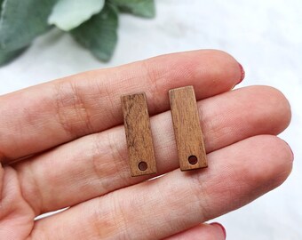 May include: Two brown wooden rectangular tags with a hole in the center. The tags are about 1 inch long and 1/2 inch wide.