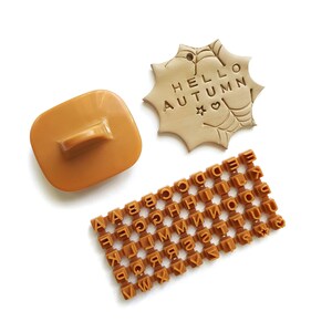 Peut inclure: Un ensemble de tampons en argile polymère marron pour l'artisanat. L'ensemble comprend l'alphabet complet, une étoile, un cœur et un tampon qui dit "Hello Autumn".