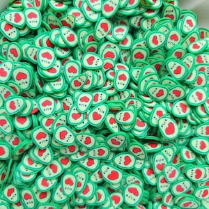 Puede incluir: Una gran cantidad de dijes en forma de aguacate verde y rojo con un corazón y una carita sonriente.