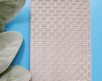 May include: A close-up of a light gray textured silicone mold with a woven pattern. The mold is labeled "Luxy Molds T-253".