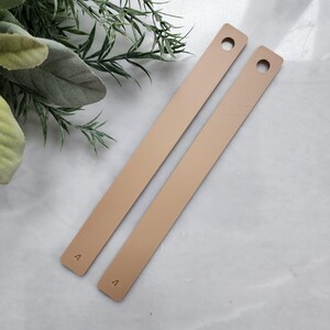 May include: Two beige leather straps with a hole at the top and the number "4" printed on the bottom.