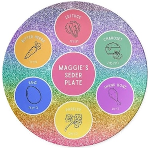May include: A round, glittery Seder plate with a rainbow gradient. It features colorful circles with illustrations and text for traditional Seder items: lettuce, bitter herbs, charoset, shank bone, parsley, and egg. The plate is labeled "Maggie's Seder Plate."