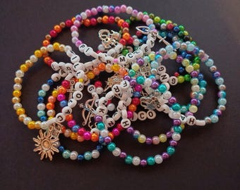May include: A pile of colourful beaded bracelets with letter charms. The charms spell out names like "Leo", "Jill", "McE", "Frank", "Co", "Ha", and "So".