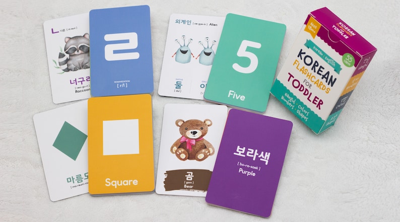 May include: A set of colorful flashcards for toddlers featuring Korean words, English translations, and illustrations. The cards include numbers, colors, shapes, and animals. The cards are part of a larger set titled "Korean Flashcards for Toddler".
