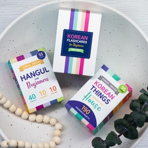 May include: Three boxes of Korean language flashcards. One box is white with a blue label that reads "Korean Flashcards for Beginners Gift Set". Another box is labeled "Hangul for Beginners" with 55 cards. The third box is labeled "Korean Things Around the House" with 95 cards.