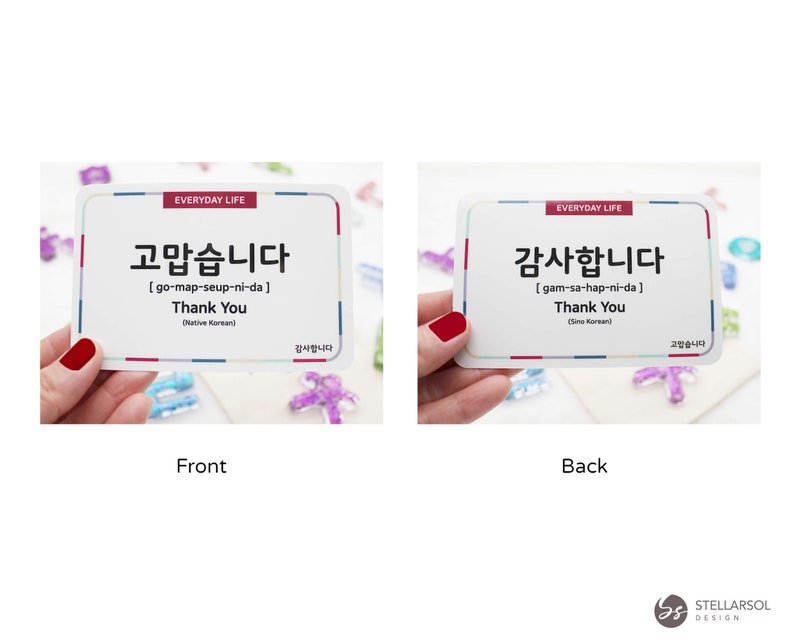 May include: Two white cards with red and blue borders. The front card says "고맙습니다" in Korean, which translates to "Thank You" in English. The back card says "감사합니다" in Korean, which also translates to "Thank You" in English. Both cards have the words "Everyday Life" printed on them.