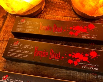 May include: Three boxes of Vampire Blood incense, each with a black background and red splatter paint. The boxes are stacked on top of each other. The text "Vampire Blood Incense" is printed in white on the front of each box. The text "Premium Vampire Extract 15g Incense" is printed in white on the bottom of each box.