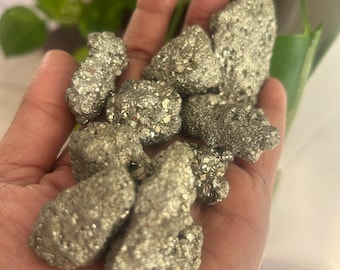 May include: A collection of raw pyrite crystals, also known as fool's gold, in various sizes and shapes. The crystals have a metallic, silver-gold color and a rough, textured surface.