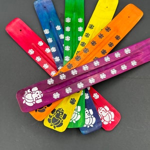 May include: A set of eight incense sticks with a rainbow of colours and a white elephant design. The sticks are made of wood and are approximately 10 inches long.