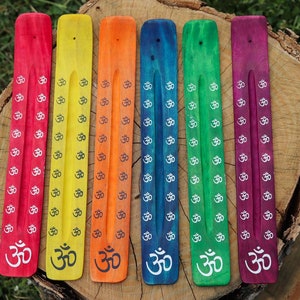 May include: Six wooden incense sticks with the Om symbol printed on them. The sticks are painted in rainbow colours, starting with red and ending with purple.
