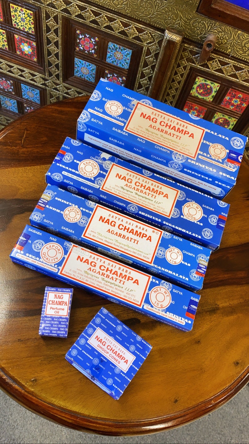 May include: A stack of blue boxes of Nag Champa incense sticks. The boxes are labeled with the brand name "Satya Sai Baba" and the product name "Nag Champa Agarbatti". There is also a small blue box of Nag Champa dhoop cones.