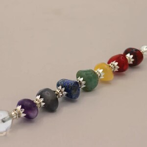 May include: A crystal wand with seven chakra stones, including amethyst, clear quartz, smoky quartz, lapis lazuli, green aventurine, yellow citrine, and red carnelian.