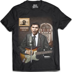 May include: A black t-shirt featuring a graphic of a person in a suit playing an electric guitar in front of a microphone and a jukebox. Above the person is a framed portrait and a sign with the text IT'S NOT MY FIRST OR MY LAST.