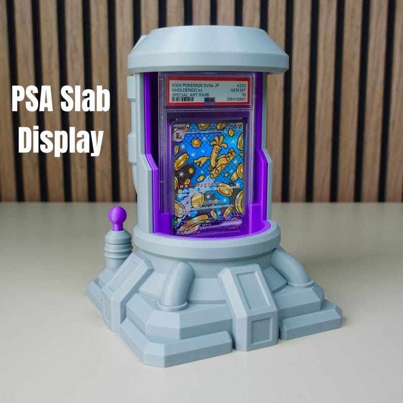 Pode incluir: Um expositor de placas PSA cinza com interior roxo, segurando um cart&atilde;o Pok&eacute;mon. O expositor tem um design futurista com o texto "PSA Slab Display" no lado esquerdo. O cart&atilde;o &eacute; vis&iacute;vel dentro.