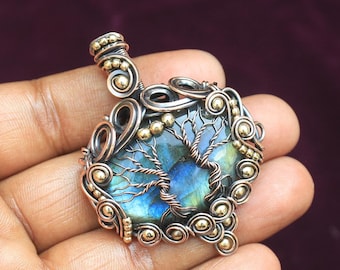 May include: A wire-wrapped pendant featuring a blue and green labradorite gemstone. The pendant is made with copper wire and gold beads, and has a tree-like design.