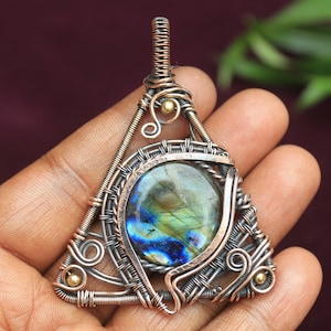 May include: A triangular pendant featuring a copper wire design and a blue-green labradorite gemstone at its centre.