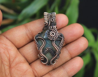 May include: A green gemstone pendant wrapped in copper wire. The wire is intricately woven around the stone, creating a unique and delicate design.