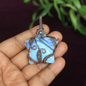 May include: A blue opal gemstone wrapped in copper wire, shaped like a star, and set as a pendant.