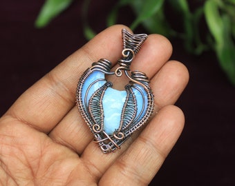 May include: A blue opal gemstone pendant wrapped in copper wire, creating a heart shape.