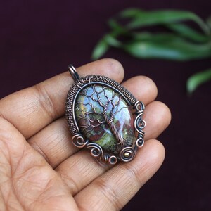 K&ouml;nnte beinhalten: Ein Anh&auml;nger aus Kupferdraht mit einem Baum des Lebens Design und einem gr&uuml;nen, braunen und roten Achat Stein.