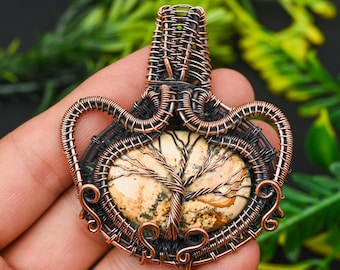 May include: A copper wire wrapped pendant featuring a tree agate stone with a natural tree pattern. The pendant is a unique and intricate piece of jewelry.