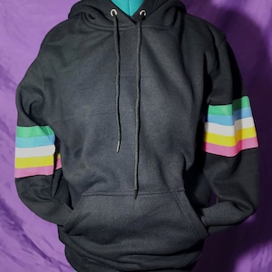 May include: Black hooded sweatshirt with a colourful striped pattern on the sleeves. The stripes are pink, yellow, light blue, and green.