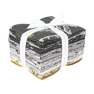 May include: A stack of fabric squares in various patterns, tied with a white ribbon. The fabrics feature designs in black, white, and gold. The ribbon is printed with text. The edges of the fabric are gold.