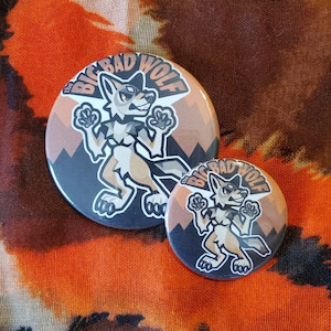 May include: Two round buttons with a cartoon wolf illustration. The buttons feature a wolf character with the text "The Big Bad Wolf" in a circular design. The background is a gradient of brown and black.