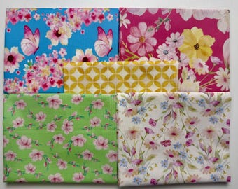 Könnte beinhalten: Fünf rechteckige Stoffmuster mit verschiedenen Mustern. Eines in Blau mit rosa Schmetterlingen und Blumen, eines in Magenta mit großen gelben und weißen Blumen, eines in Gelb mit weißem geometrischem Gitter, eines in Grün mit rosa Blüten und eines in Weiß mit kleinen Blumen.