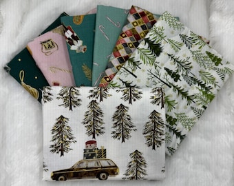 Könnte beinhalten: Eine Sammlung von Stoffquadraten mit Weihnachtsmotiven und verschiedenen Mustern. Designs umfassen Weihnachtsbäume, Zuckerstangen und einen Kombi mit Geschenken. Farben sind Grün, Weiß, Rosa und Gold. Der Stoff ist auf einer weißen, flauschigen Oberfläche angeordnet.