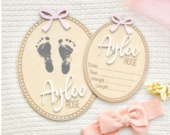 Letrero personalizado de madera para anuncio de nacimiento de niña con huella y lazo rosa.