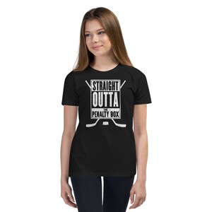 May include: Black youth t-shirt with a white graphic that says "Straight Outta The Penalty Box" with hockey sticks and a puck.