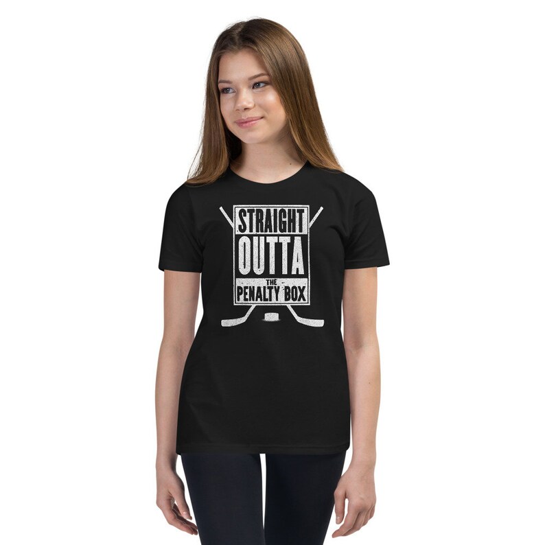 May include: Black youth t-shirt with a white graphic that says "Straight Outta The Penalty Box" with hockey sticks and a puck.