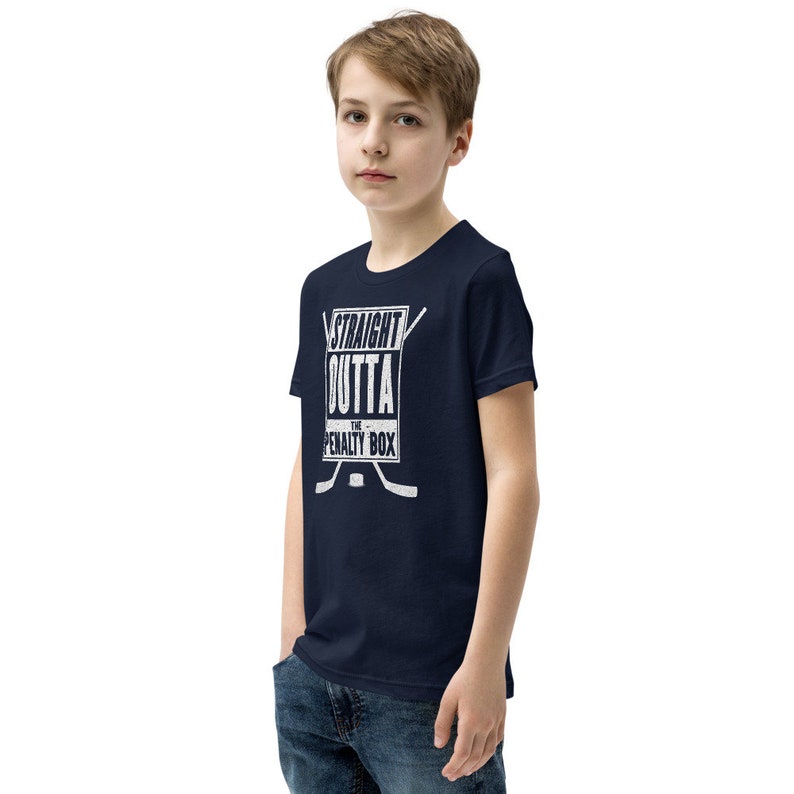 May include: A navy blue youth t-shirt with a white graphic that says "Straight Outta The Penalty Box" with hockey sticks and a puck.