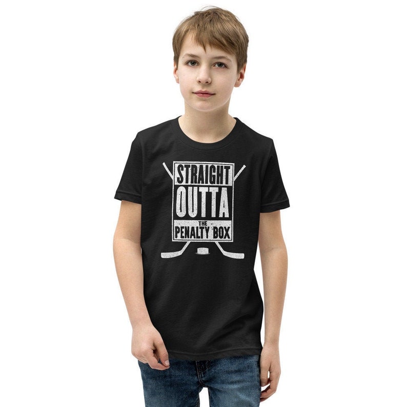 May include: Black youth t-shirt with a white graphic that says "Straight Outta The Penalty Box" with hockey sticks crossed over the box.