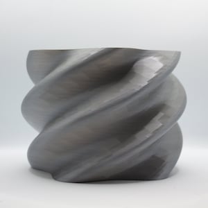 Peut inclure: Un vase gris en spirale imprimé en 3D.